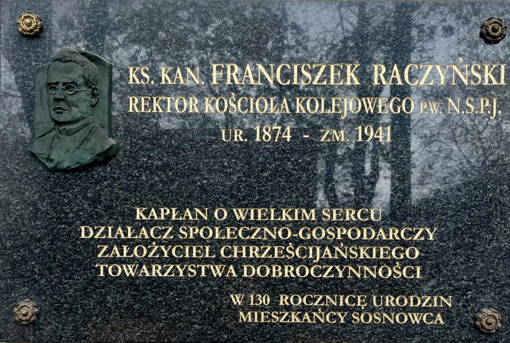 Tablica pamiątkowa ks. kan. Franciszka Raczyńskiego, rektora Kościoła Kolejowego w Sosnowcu, z płaskorzeźbionym portretem duchownego i złotym napisem upamiętniającym jego działalność społeczną i gospodarczą.
