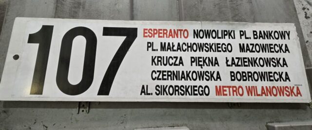 Tablica boczna z linii nr 107 klejona z dwóch naklejek na płycie PCV. Trasa z 2025 r.| Źródło: Miejskie Zakłady Autobusowe sp. z o.o. w Warszawie, zajezdnia R-1 "Woronicza"|